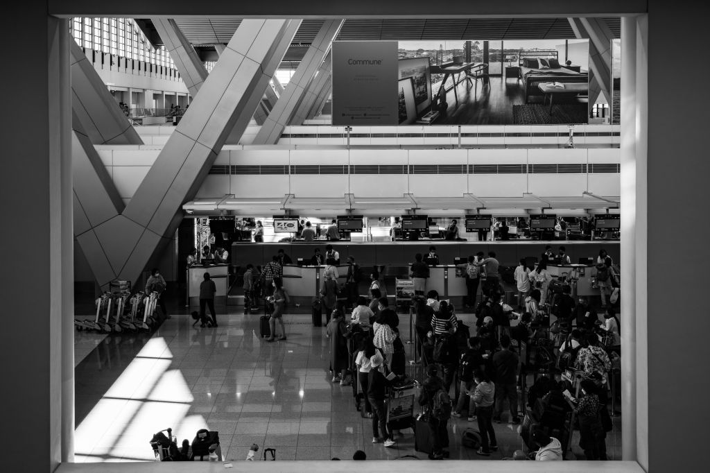 Overhead view of a crowded airport check-in counter with travelers and luggage