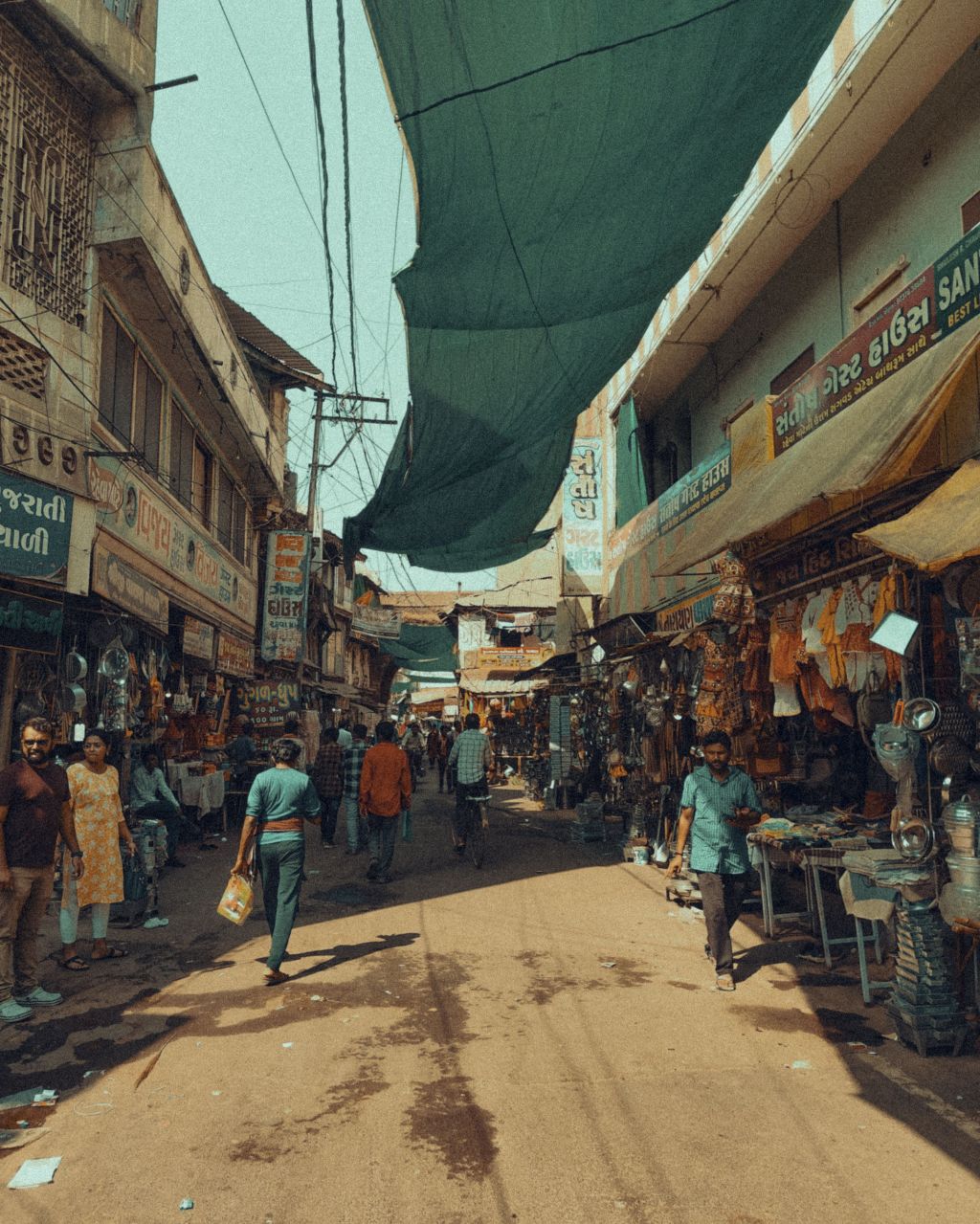 A busy market street in an Indian town with shopkeepers, awnings and pedestrians