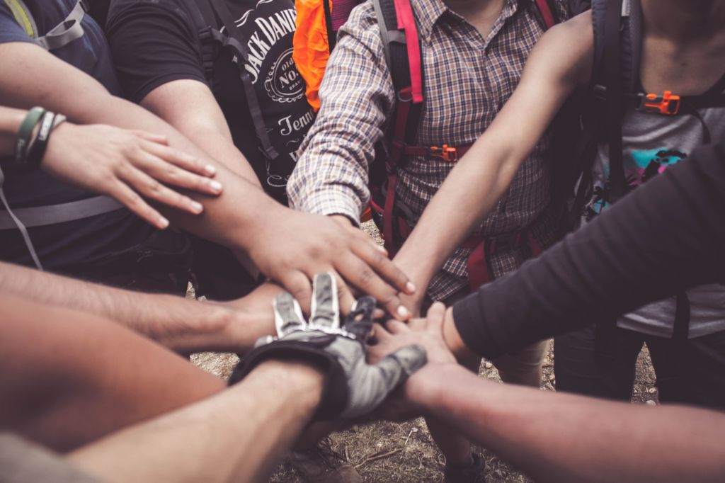 A group of hikers stacking their hands together in a show of trust and teamwork